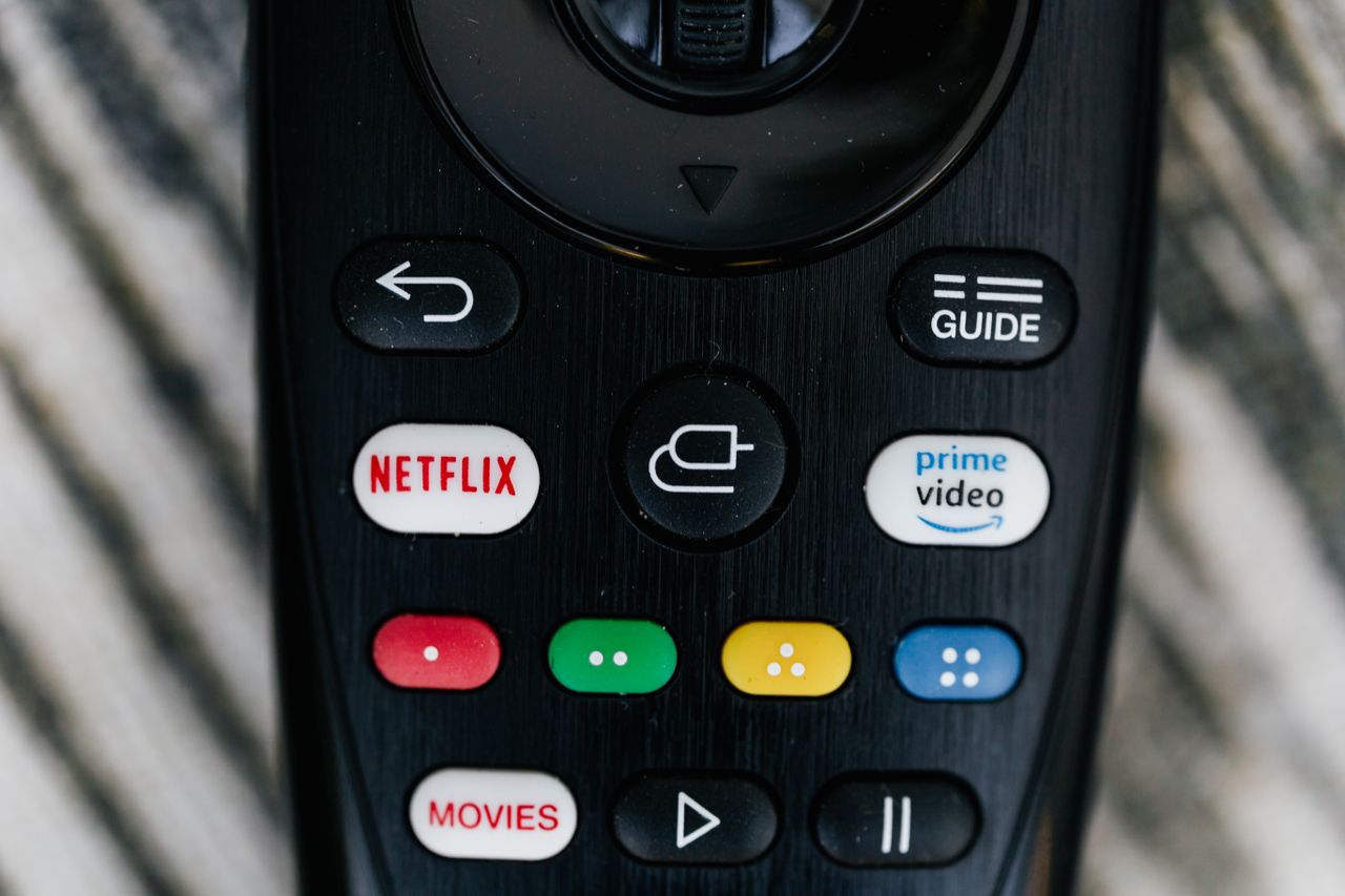 Contact Detailed close-up image of a TV remote control with streaming service buttons.